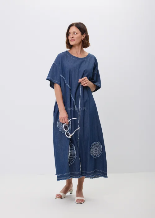 Jeansowa sukienka maxi oversize z krótkim, szerokim rękawem, ozdobiona dekoracyjnymi przeszyciami oraz naszywanymi aplikacjami w kształcie okręgów z postrzępionym wykończeniem. Luźny fason zapewnia wygodę i tworzy nowoczesną, casualową stylizację.