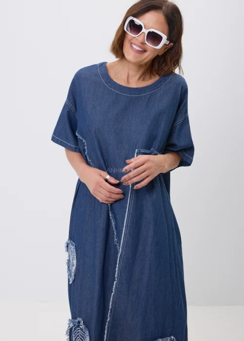 Jeansowa sukienka maxi oversize z krótkim, szerokim rękawem, ozdobiona dekoracyjnymi przeszyciami oraz naszywanymi aplikacjami w kształcie okręgów z postrzępionym wykończeniem. Luźny fason zapewnia wygodę i tworzy nowoczesną, casualową stylizację.