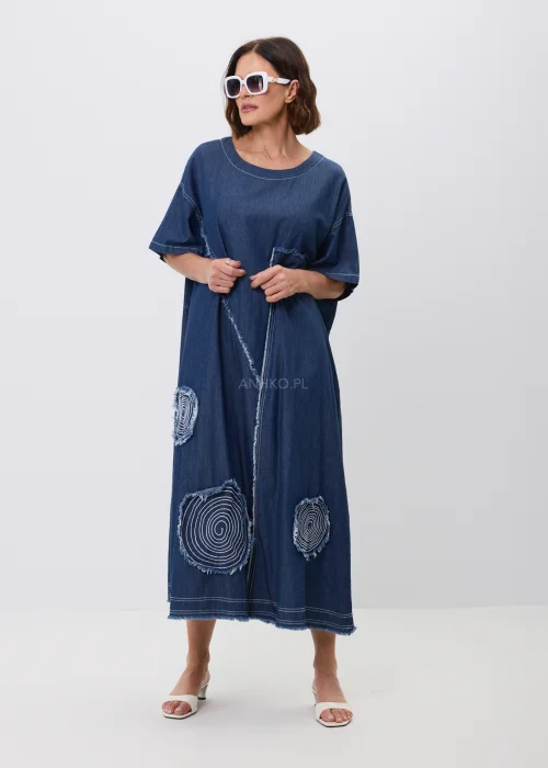 Jeansowa sukienka maxi oversize z krótkim, szerokim rękawem, ozdobiona dekoracyjnymi przeszyciami oraz naszywanymi aplikacjami w kształcie okręgów z postrzępionym wykończeniem. Luźny fason zapewnia wygodę i tworzy nowoczesną, casualową stylizację.