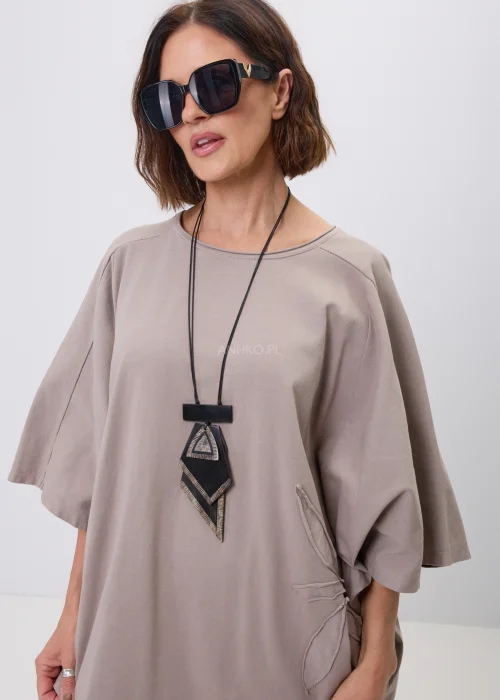 Beżowa bluzka oversize z szerokim rękawem 3/4 i ozdobną aplikacją kwiatową z przeszyciami na dole. Minimalistyczny fason oraz luźny krój zapewniają wygodę i doskonale wpisują się w nowoczesne, casualowe stylizacje.