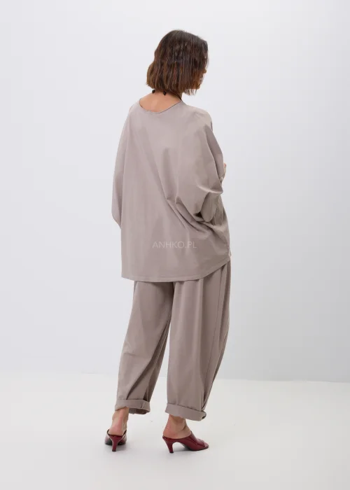 Beżowa bluzka oversize z szerokim rękawem 3/4 i ozdobną aplikacją kwiatową z przeszyciami na dole. Minimalistyczny fason oraz luźny krój zapewniają wygodę i doskonale wpisują się w nowoczesne, casualowe stylizacje.