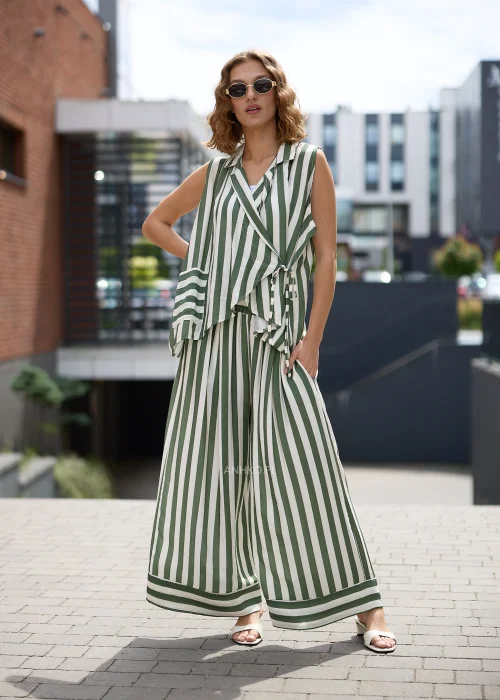Zielono-białe spodnie damskie w pionowe paski z szerokimi nogawkami i luźnym fasonem, wykonane z lekkiego materiału, prezentowane w eleganckiej miejskiej stylizacji.