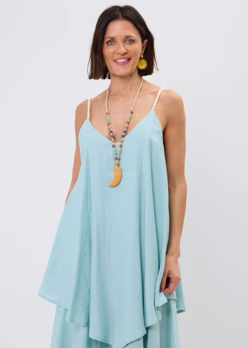 Błękitna sukienka maxi damska na cienkich ramiączkach z ozdobnym splotem, o luźnym fasonie i wielowarstwowych falbanach. Zwiewny model w stylu boho uzupełniony kolorowym naszyjnikiem i letnimi dodatkami.