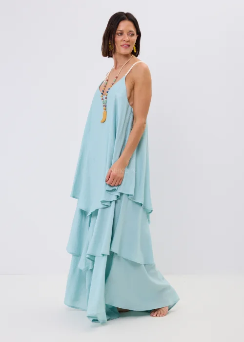 Błękitna sukienka maxi damska na cienkich ramiączkach z ozdobnym splotem, o luźnym fasonie i wielowarstwowych falbanach. Zwiewny model w stylu boho uzupełniony kolorowym naszyjnikiem i letnimi dodatkami.