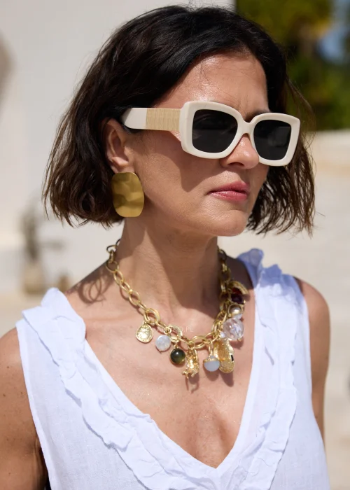 Kremowe damskie okulary przeciwsłoneczne o geometrycznej, lekko kociej oprawce z ciemnymi szkłami i szerokimi zausznikami w beżowym odcieniu. Stylowy model inspirowany modą retro.