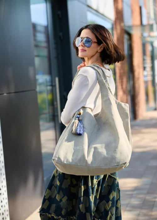 Duża beżowa torba typu shopper z miękkiej tkaniny z ozdobnym chwostem i drewnianymi koralikami.