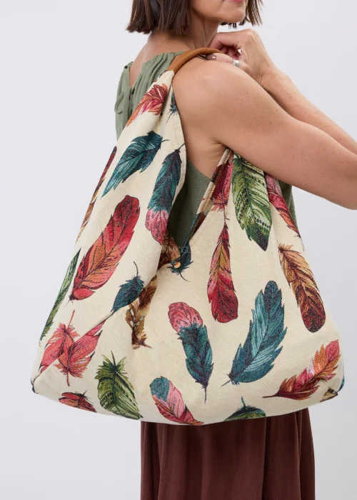 Duża materiałowa torba shopper w kremowym kolorze ozdobiona wielobarwnym wzorem piór. Pojemny model z wygodnymi uchwytami, idealny do codziennych stylizacji, na zakupy, spacer lub wyjazd.