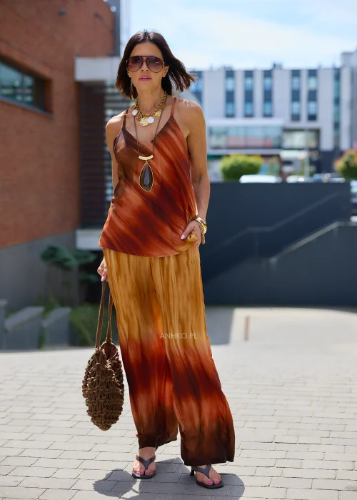 Zwiewne spodnie palazzo z efektem ombre w odcieniach karmelu, miedzi i ciemnego brązu. Szerokie nogawki oraz lekko kreszowana tkanina nadają modelowi elegancki, płynny wygląd idealny do stylizacji boho i resort.