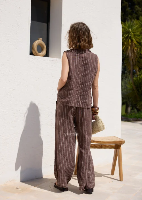 Brązowa lniana kamizelka damska w białe paski z klapami i guzikami, zestawiona z pasującymi spodniami, tworzy elegancki komplet w stylu casual.