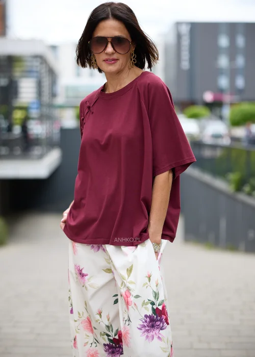 Bordowa bluzka o luźnym oversize'owym fasonie z okrągłym dekoltem, krótkimi szerokimi rękawami i ozdobnymi wiązaniami inspirowanymi stylem orientalnym przy ramieniu.