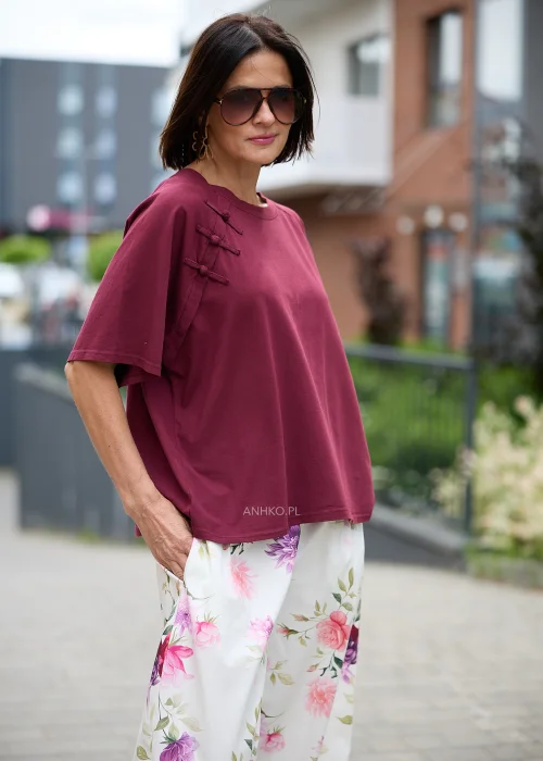 Bordowa bluzka o luźnym oversize'owym fasonie z okrągłym dekoltem, krótkimi szerokimi rękawami i ozdobnymi wiązaniami inspirowanymi stylem orientalnym przy ramieniu.