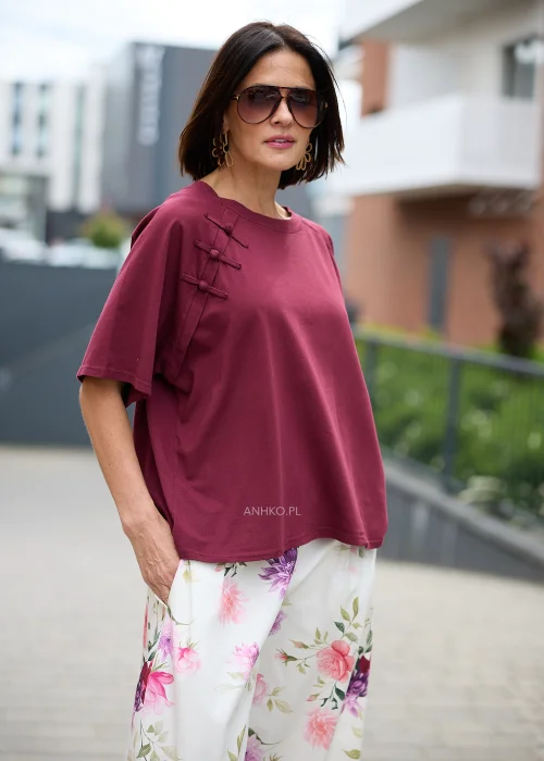 Bordowa bluzka o luźnym oversize'owym fasonie z okrągłym dekoltem, krótkimi szerokimi rękawami i ozdobnymi wiązaniami inspirowanymi stylem orientalnym przy ramieniu.