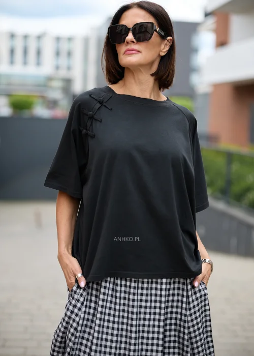 Czarna bluzka o luźnym fasonie z krótkimi rękawami i szerokim dekoltem typu łódka. Ozdobne zapięcia inspirowane stylem orientalnym umieszczone przy ramieniu nadają jej oryginalnego charakteru