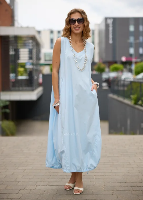 Sukienka maxi w błękitnym kolorze to propozycja dla kobiet, które cenią wygodę i minimalistyczną elegancję. Luźny fason typu bombka swobodnie układa się na sylwetce, a dekolt w kształcie litery V subtelnie podkreśla szyję.