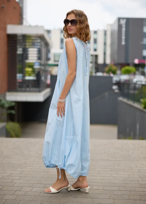 Sukienka maxi w błękitnym kolorze to propozycja dla kobiet, które cenią wygodę i minimalistyczną elegancję. Luźny fason typu bombka swobodnie układa się na sylwetce, a dekolt w kształcie litery V subtelnie podkreśla szyję.