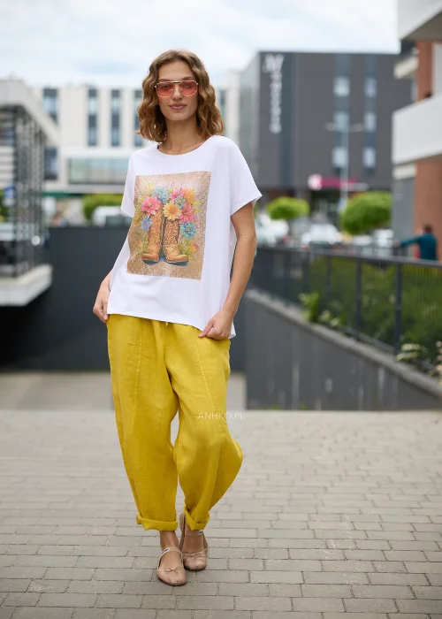 Biały t-shirt damski z efektownym nadrukiem kowbojskich botków wypełnionych kolorowymi kwiatami na beżowym tle.