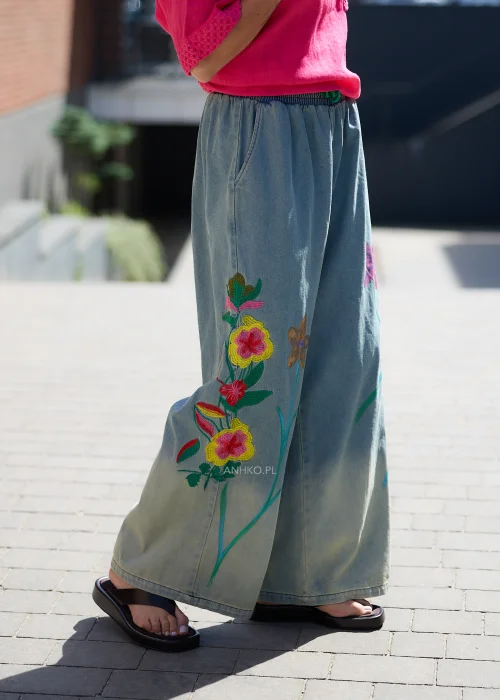 Szerokie spodnie z miękkiego denimu w odcieniu szaroniebieskim z kolorowym haftem kwiatowym na nogawkach.