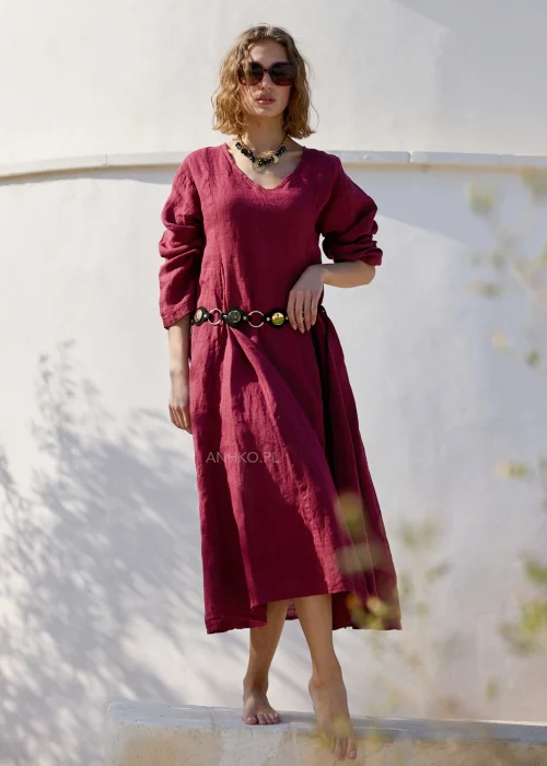 Bordowa lniana sukienka midi z dekoltem V i długimi rękawami o luźnym, naturalnym fasonie. Minimalistyczny krój podkreśla elegancję stylizacji w klimacie boho i slow fashion.