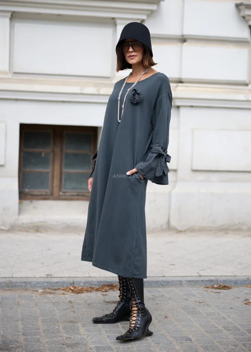 Ciemnoszara sukienka oversize midi z szerokimi rękawami i wiązaniami, ozdobny kwiat na piersi, stylizacja z botkami.