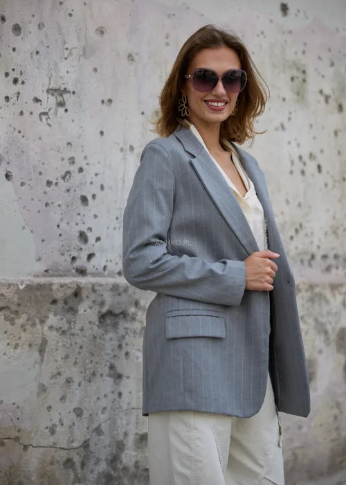 Szara marynarka damska oversize w delikatny jasny prążek, z szerokimi klapami, zapięciem na jeden guzik i kieszeniami z klapami.