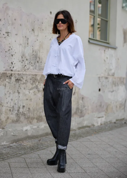 Bluzka damska oversize w białym kolorze, z dekoltem V, ozdobnym zapięciem na materiałowe pętelki i supełki oraz długimi rękawami z możliwością podpięcia.