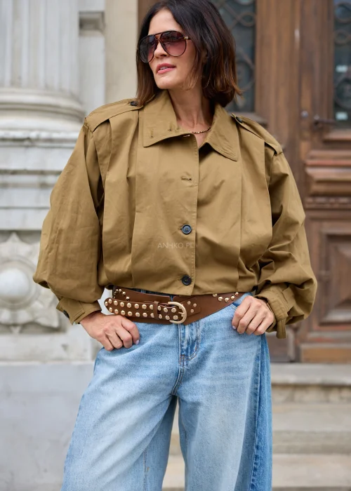 Brązowy szeroki pasek damski z dużymi srebrnymi aplikacjami, metalowymi nitami oraz klasyczną klamrą z bolcem. Wyrazisty model inspirowany stylem rockowym i western.