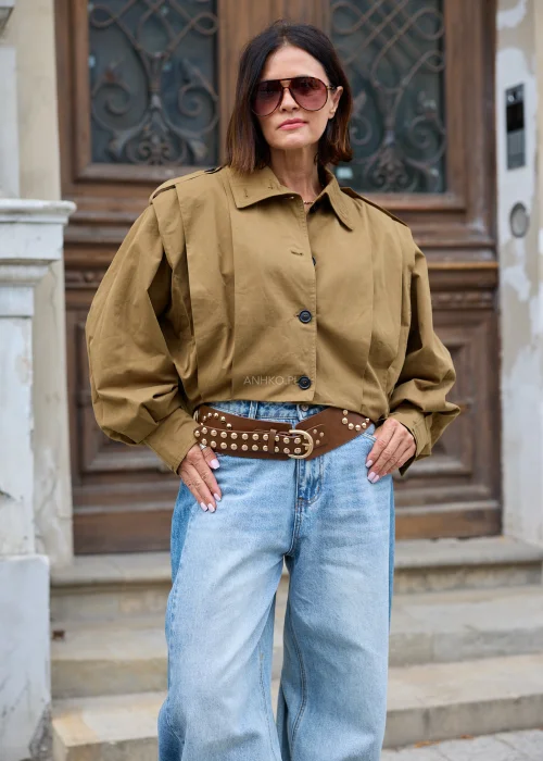 Brązowy szeroki pasek damski z dużymi srebrnymi aplikacjami, metalowymi nitami oraz klasyczną klamrą z bolcem. Wyrazisty model inspirowany stylem rockowym i western.