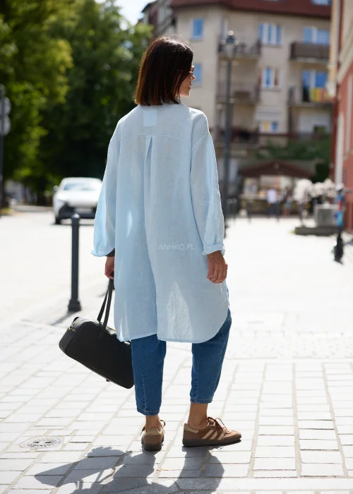 Koszula damska oversize w jasnobłękitnym kolorze, o wydłużonym fasonie z długimi rękawami, klasycznym kołnierzykiem i lekką, naturalnie układającą się tkaniną.
