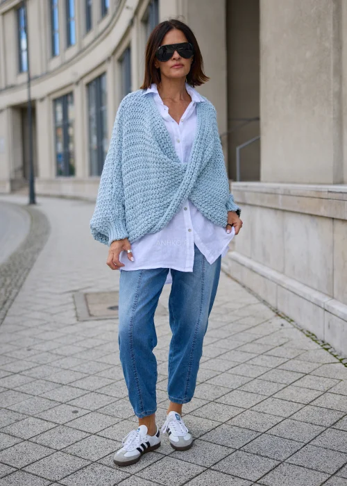 Sweter damski oversize w jasnobłękitnym kolorze, o grubym strukturalnym splocie, z kopertowym przodem i szerokimi długimi rękawami.