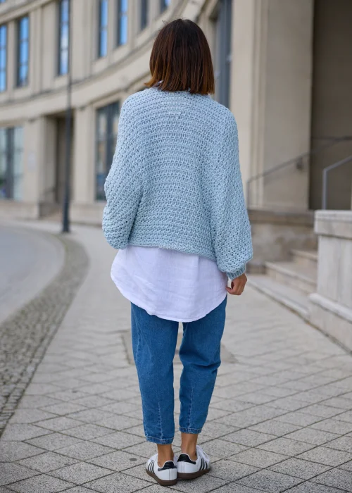 Sweter damski oversize w jasnobłękitnym kolorze, o grubym strukturalnym splocie, z kopertowym przodem i szerokimi długimi rękawami.