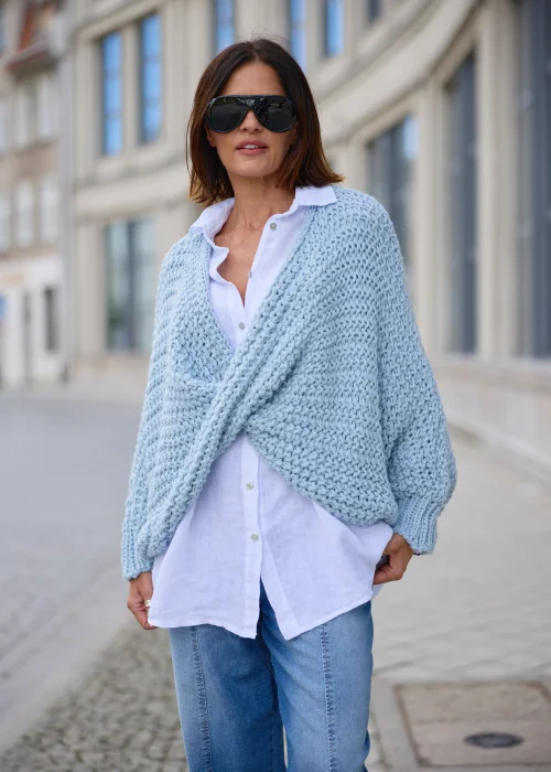Sweter damski oversize w jasnobłękitnym kolorze, o grubym strukturalnym splocie, z kopertowym przodem i szerokimi długimi rękawami.