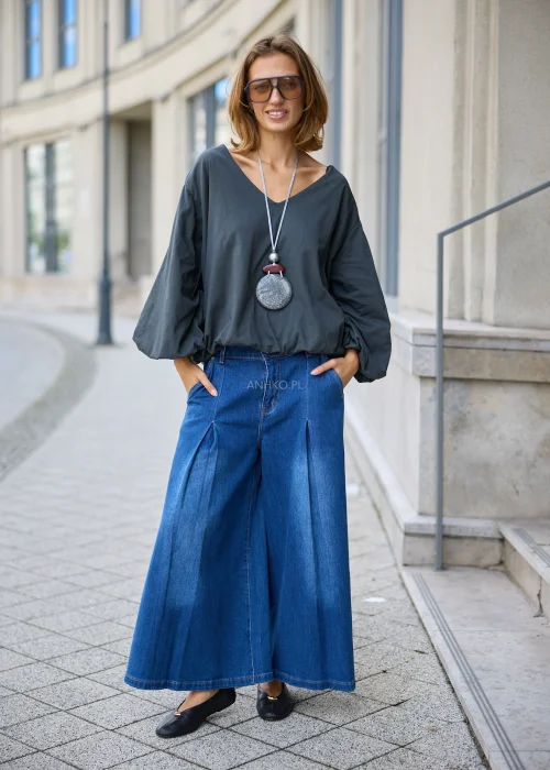 Jeansy damskie w niebieskim kolorze, o szerokim fasonie wide leg z wysokim stanem, zakładkami z przodu i przeszyciami podkreślającymi nogawki.
