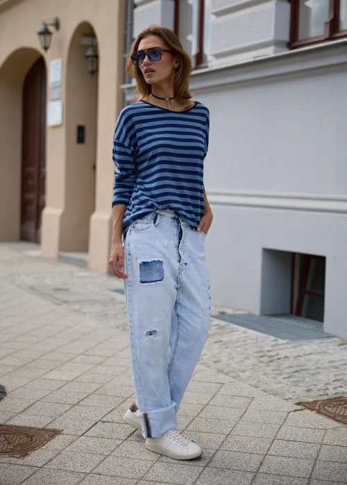 Bluzka damska oversize w granatowo-niebieskie paski, z szerokim okrągłym dekoltem, obniżoną linią ramion i długimi rękawami.
