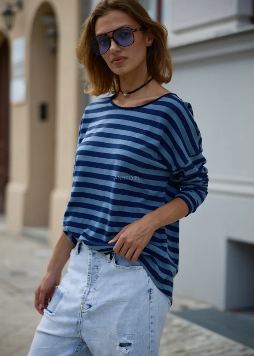 Bluzka damska oversize w granatowo-niebieskie paski, z szerokim okrągłym dekoltem, obniżoną linią ramion i długimi rękawami.
