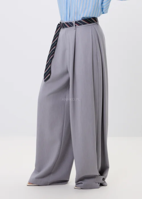 Szare spodnie damskie wide leg z szerokimi nogawkami i ozdobnymi patkami z guzikami przy dole nogawek.