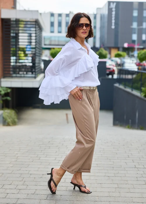 Spodnie Starola Rose Cappuccino w odcieniu ciepłego beżu, z podwiniętą nogawką i eleganckim paskiem, w minimalistycznej stylizacji z butami na obcasie.