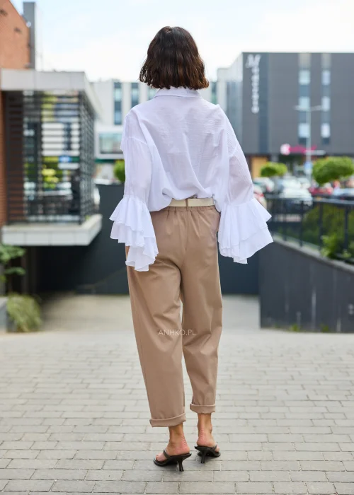 Spodnie Starola Rose Cappuccino w odcieniu ciepłego beżu, z podwiniętą nogawką i eleganckim paskiem, w minimalistycznej stylizacji z butami na obcasie.