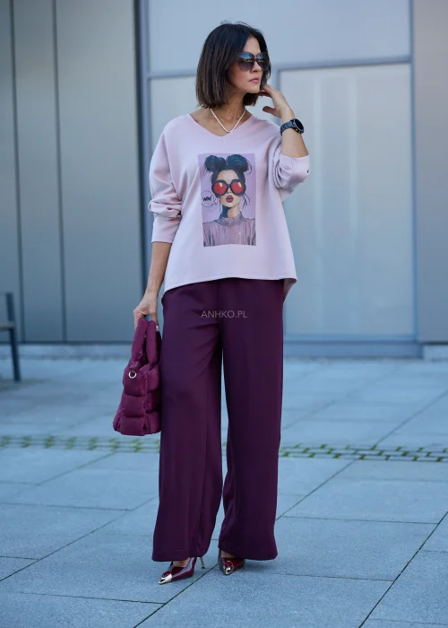 Bluzka damska oversize w pudroworóżowym kolorze, z długimi rękawami, okrągłym dekoltem i nadrukiem kobiety w okularach.