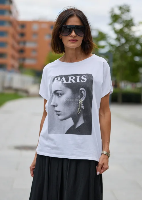 Biały T-shirt damski o luźnym kroju, z czarno-białym nadrukiem kobiety, napisem Paris i ozdobną aplikacją przy uchu.