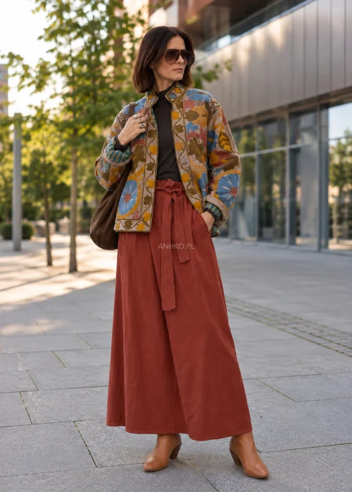 Spódnica sztruksowa maxi w kolorze ceglastym z wysokim stanem i paskiem do wiązania, o rozkloszowanym fasonie, stylizowana z lekką bluzką i botkami w stylu boho.