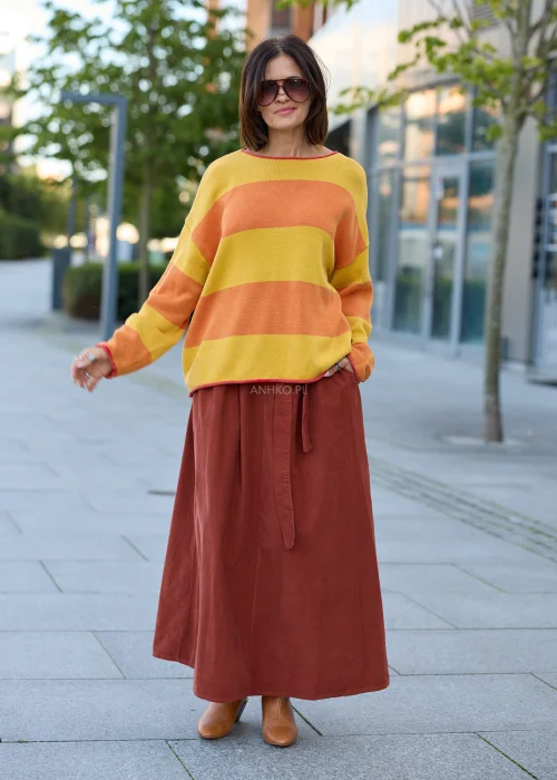 Spódnica sztruksowa maxi w kolorze ceglastym z wysokim stanem i paskiem do wiązania, o rozkloszowanym fasonie, stylizowana z lekką bluzką i botkami w stylu boho.