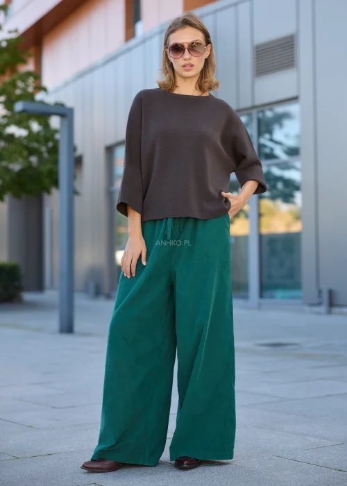 Dzianinowy sweter damski oversize w ciemnobrązowym kolorze, z szerokim fasonem, obniżoną linią ramion i luźnymi rękawami o długości 3/4.