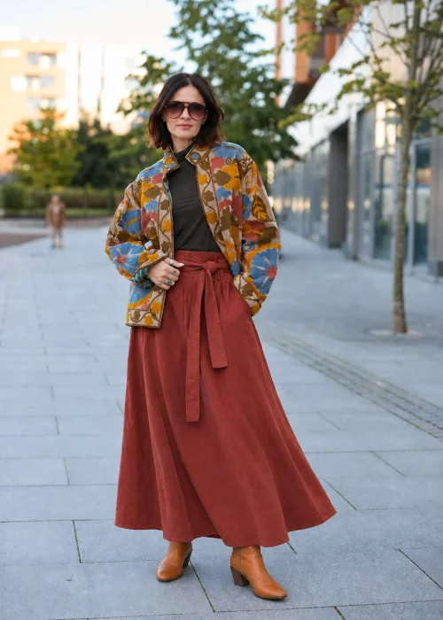 Spódnica sztruksowa maxi w kolorze ceglastym z wysokim stanem i paskiem do wiązania, o rozkloszowanym fasonie, stylizowana z lekką bluzką i botkami w stylu boho.