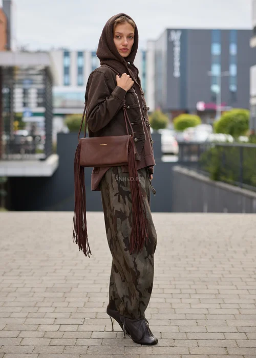 Ciemnobrązowa torebka damska Roswick o podłużnym fasonie z bardzo długimi frędzlami po bokach i paskiem ozdobionym supełkami. Model w stylu boho i westernowym.