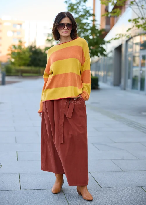 Sweter damski oversize w szerokie pasy musztardowo-pomarańczowe, z dekoltem łódkowym, długimi rękawami i kontrastowym wykończeniem.