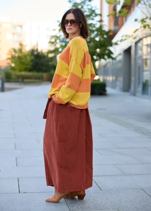 Sweter damski oversize w szerokie pasy musztardowo-pomarańczowe, z dekoltem łódkowym, długimi rękawami i kontrastowym wykończeniem.