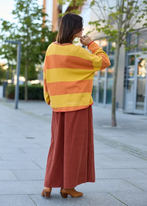 Sweter damski oversize w szerokie pasy musztardowo-pomarańczowe, z dekoltem łódkowym, długimi rękawami i kontrastowym wykończeniem.