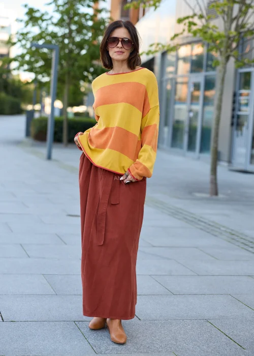 Sweter damski oversize w szerokie pasy musztardowo-pomarańczowe, z dekoltem łódkowym, długimi rękawami i kontrastowym wykończeniem.