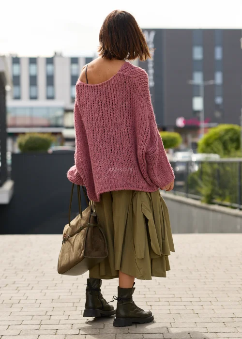 Sweter damski oversize w pudrowym różu, o ażurowym splocie, szerokich rękawach i luźnym, asymetrycznym fasonie.