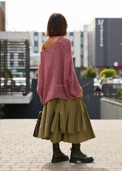 Sweter damski oversize w pudrowym różu, o ażurowym splocie, szerokich rękawach i luźnym, asymetrycznym fasonie.